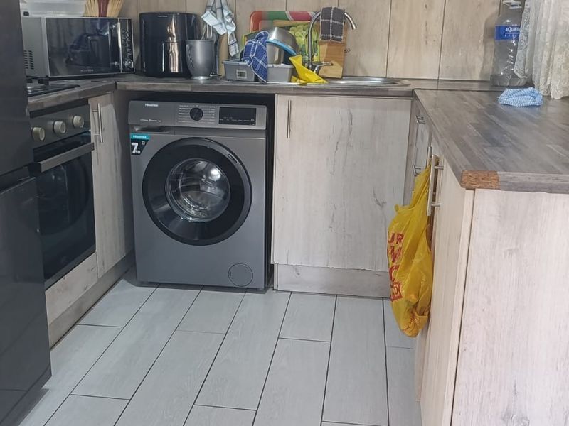 Compact kitchen featuring light wood-look cabinetry, laminate countertops, built-in oven, and tiled flooring, providing a functional workspace.