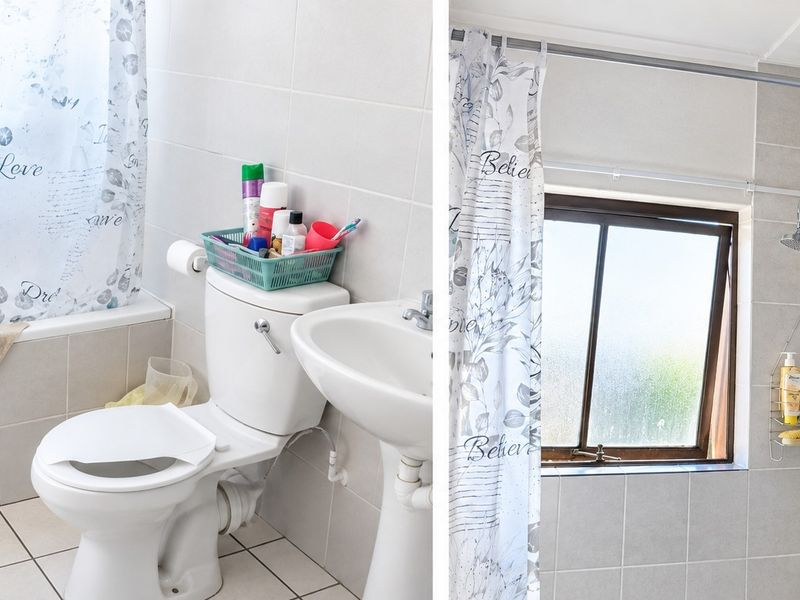 A functional bathroom featuring a bathtub with shower attachment, pedestal basin, and toilet, finished with neutral wall and floor tiling.