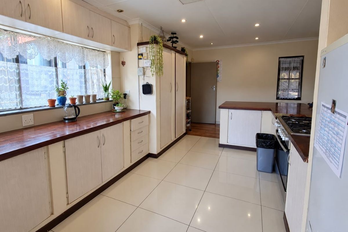 A functional kitchen featuring light-toned cabinetry, warm wooden countertops, tiled flooring, and integrated cooking appliances, offering a clean and practical workspace.