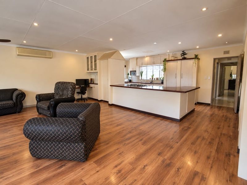 Spacious open-plan living area featuring laminate flooring, recessed lighting, and a functional kitchen with a central island and built-in cabinetry.