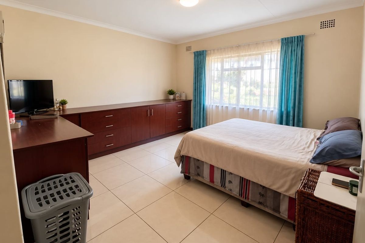 Spacious bedroom featuring neutral tiled flooring, built-in wooden cabinetry, and large windows with natural light.