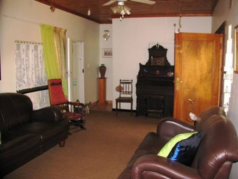 A living room featuring a timber ceiling with a ceiling fan and a wooden door, offering a traditional interior space.