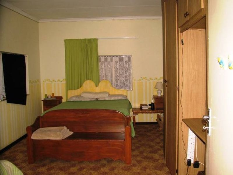 A dated bedroom featuring built-in wooden wardrobes and carpeted flooring, offering a functional space with potential for modernization.