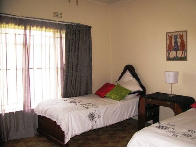 A functional bedroom featuring a large window with security bars and neutral wall finishes, providing a comfortable space for rest.