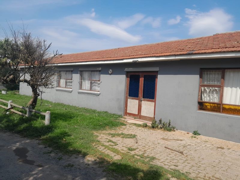 Rear exterior view of the house featuring a paved patio area, terracotta roof tiles, and security bars on the windows.