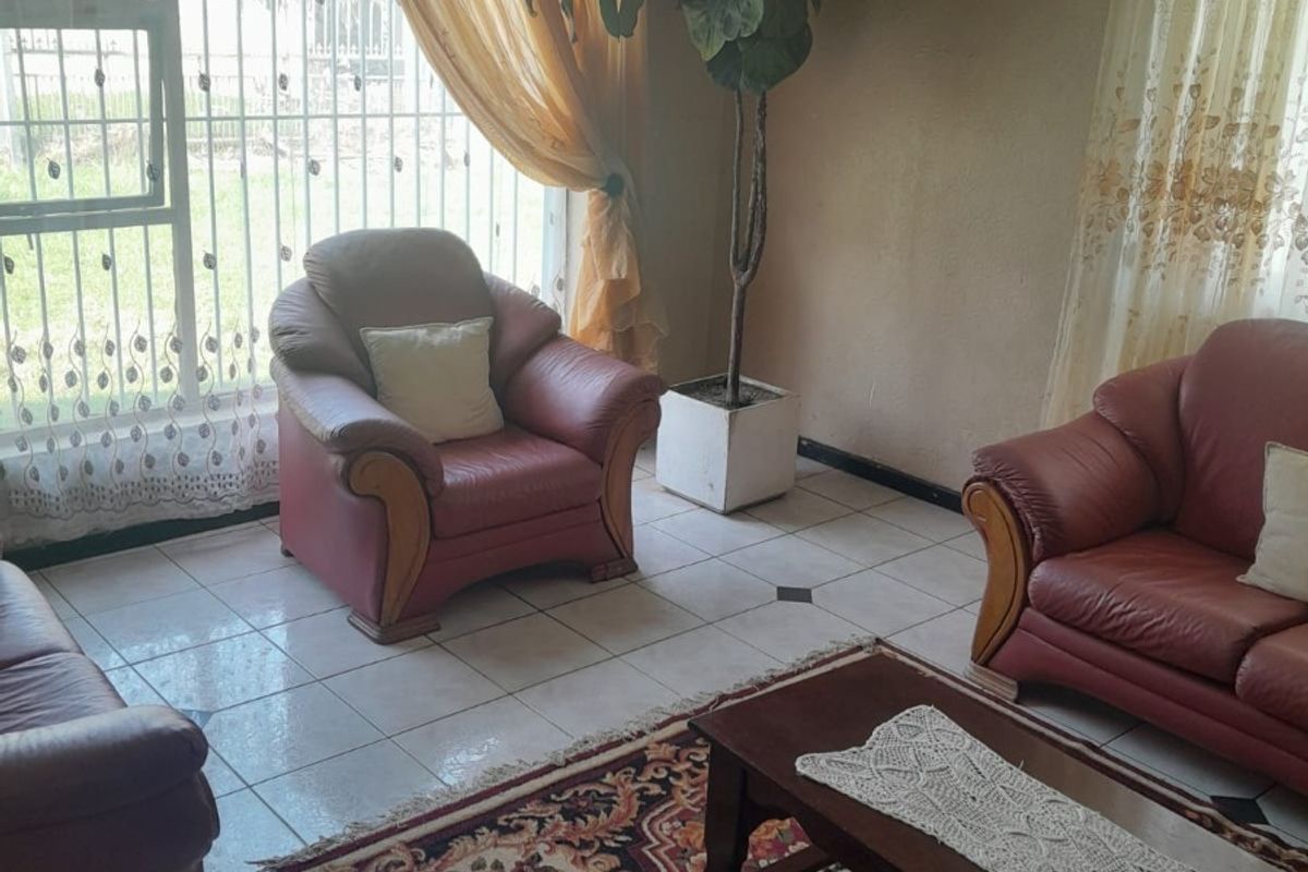 A living room featuring tiled flooring, large windows with security bars, and decorative cornice detailing.