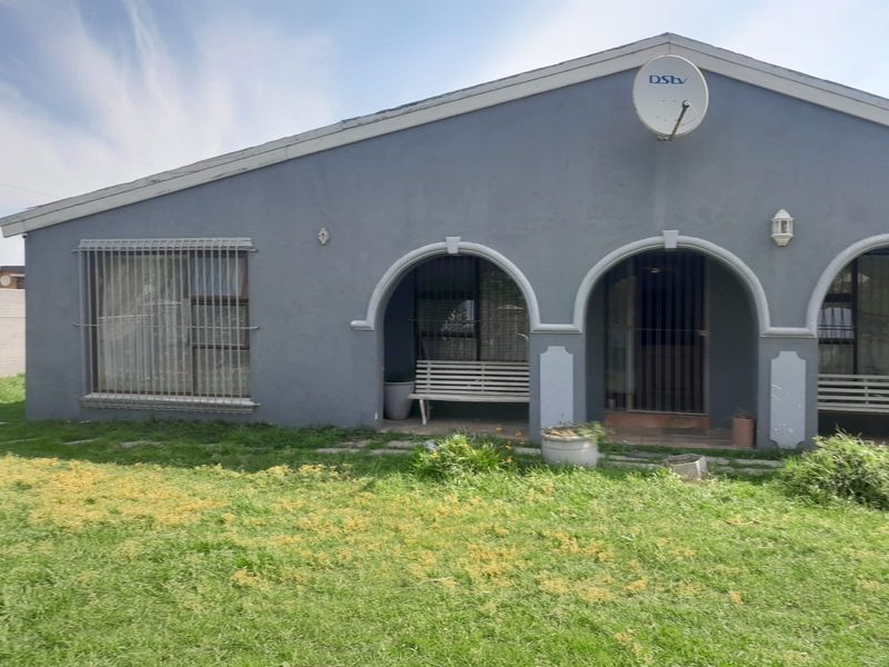 Rear view of the house featuring an arched covered patio, security bars on windows, and a satellite dish mounted on the exterior wall.