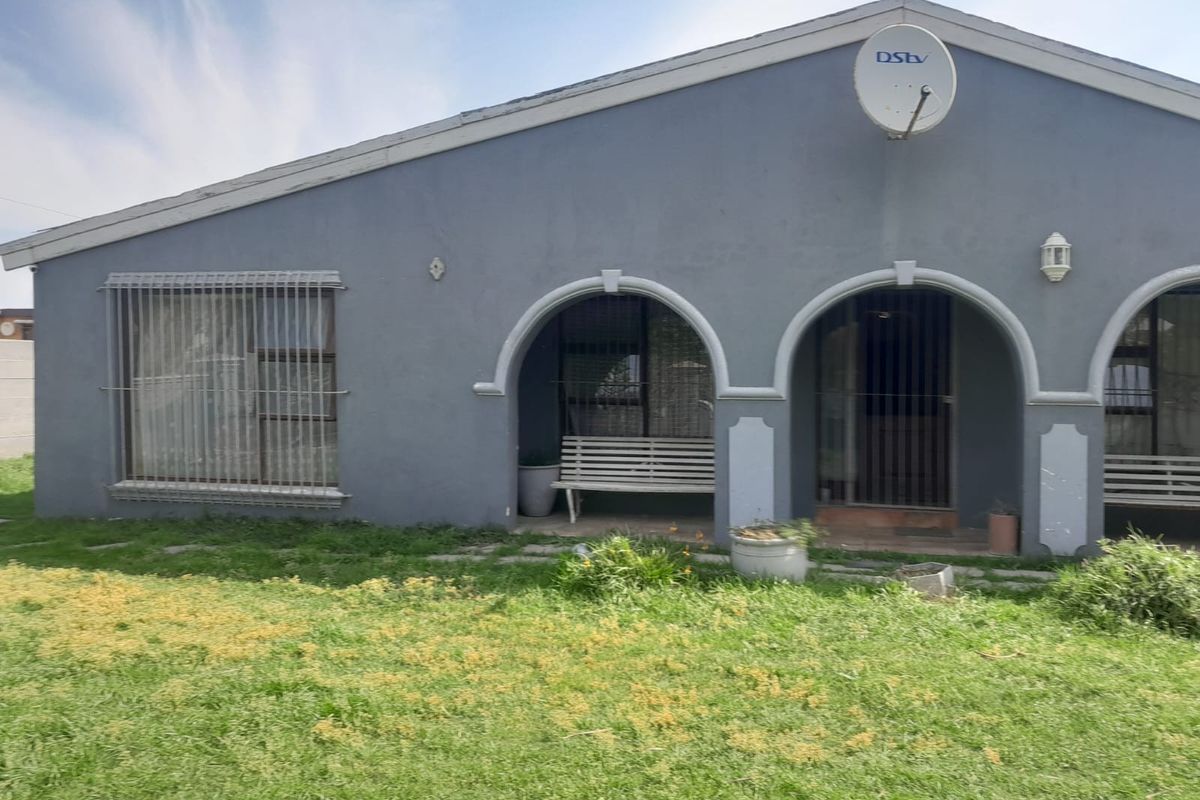 Rear view of the house featuring an arched covered patio, security bars on windows, and a satellite dish mounted on the exterior wall.