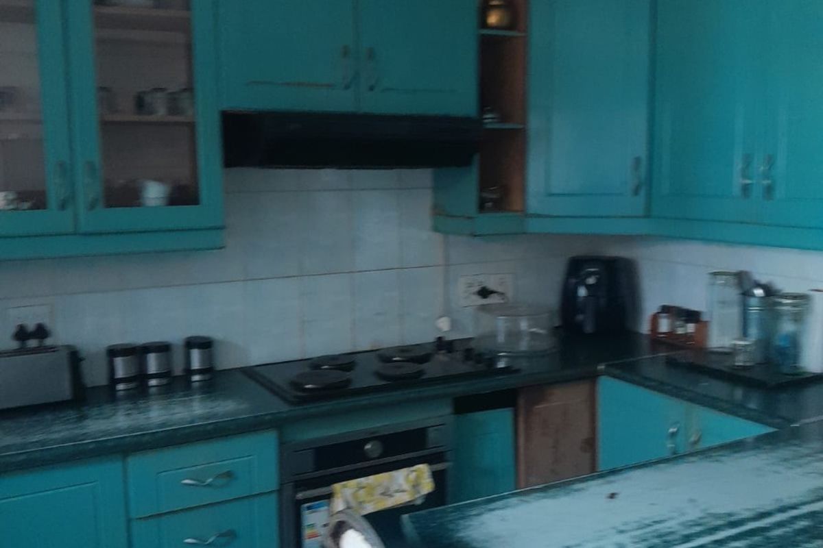 A dated kitchen featuring teal cabinetry, a gas hob, built-in oven, and tiled flooring, requiring cosmetic updates to modernize the space.