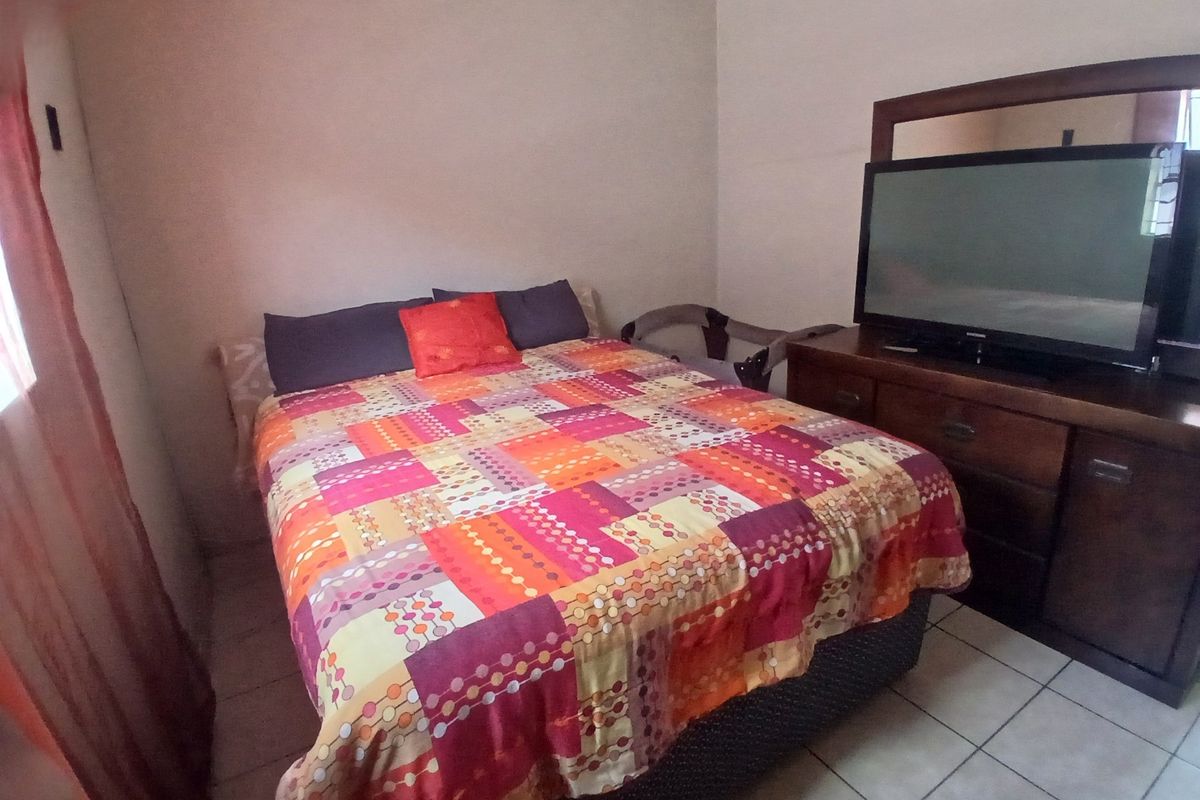 A standard bedroom featuring tiled flooring and neutral wall finishes, providing a functional space for rest.