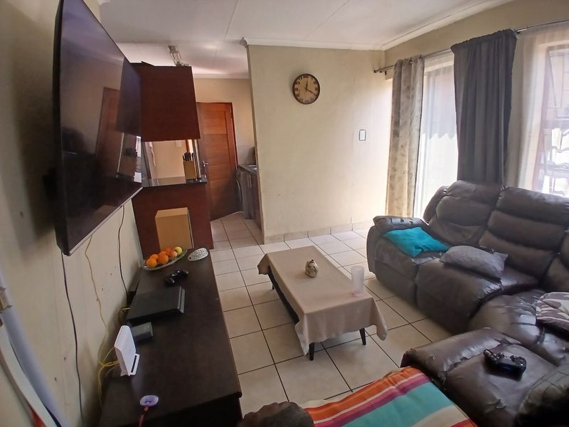 Open plan living area featuring tiled flooring and a connected kitchen space with built-in cabinetry and counter.