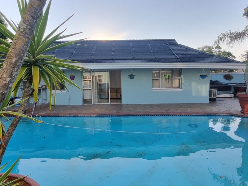 A rear view of the cottage featuring a swimming pool, tiled patio area, and direct access to the interior through sliding glass doors.