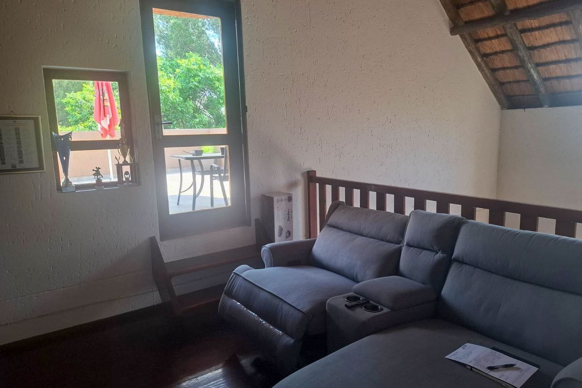A living area featuring a unique thatched roof ceiling, timber flooring, and direct access to an outdoor balcony through a glass door.