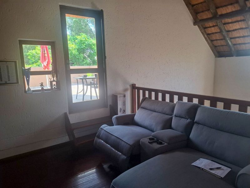 A living area featuring a unique thatched roof ceiling, timber flooring, and direct access to an outdoor balcony through a glass door.