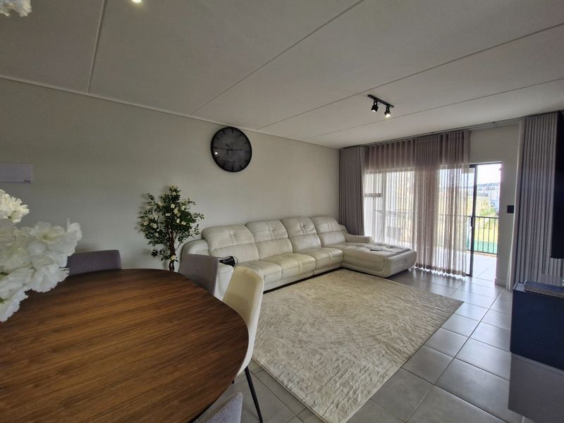 Open plan living and dining area featuring tiled flooring, modern track lighting, and large sliding glass doors leading to an outdoor balcony.