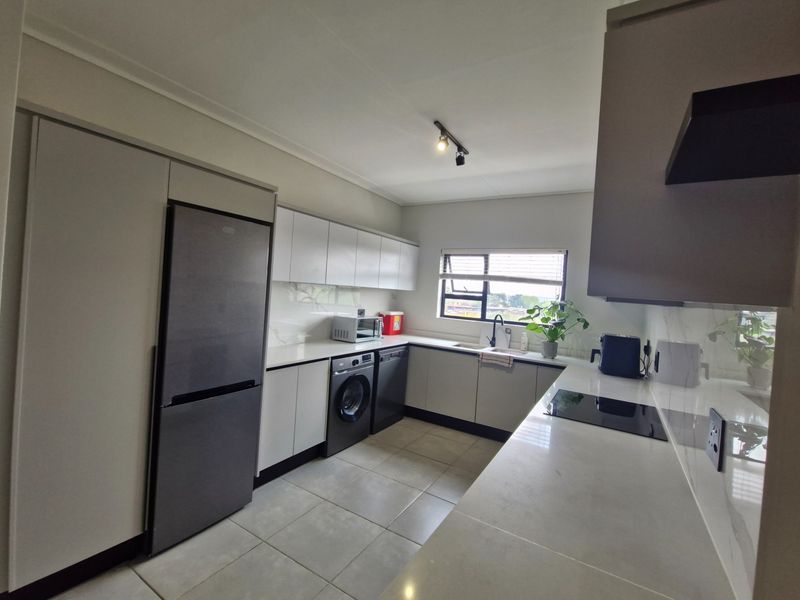 Modern kitchen featuring sleek cabinetry, stone countertops, integrated appliances, and tiled flooring, offering a clean and functional workspace.