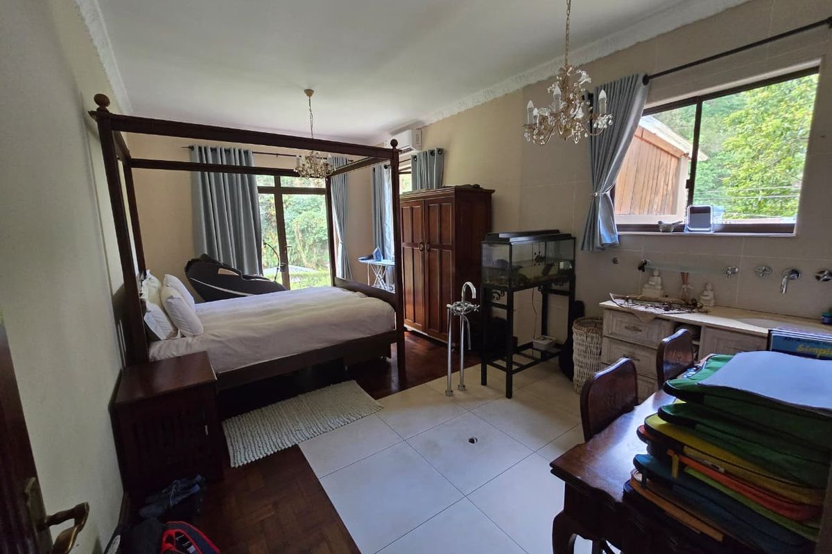 Spacious bedroom featuring a mix of parquet and tiled flooring, built-in vanity, and direct access to the outdoors via sliding glass doors.