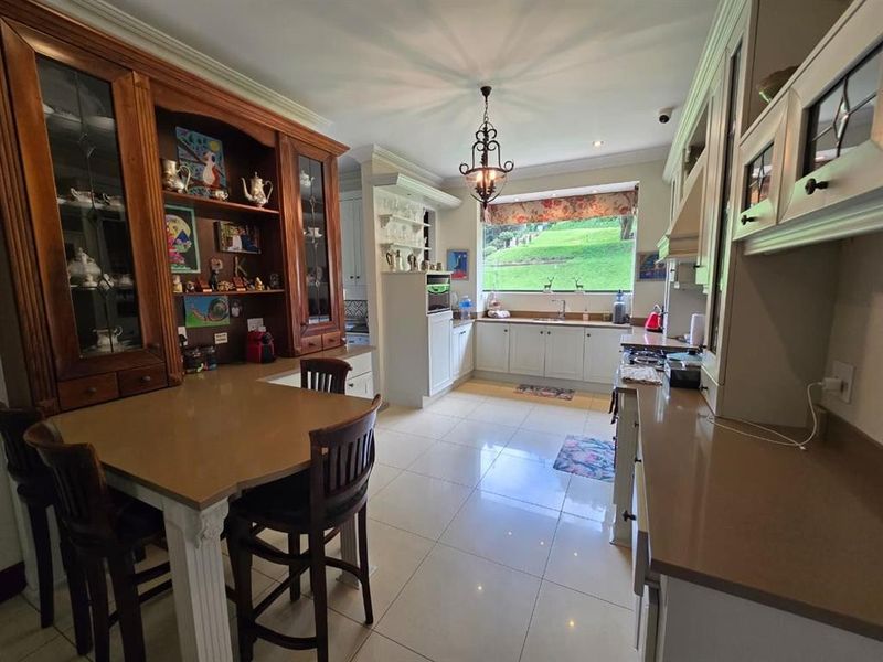 Spacious kitchen featuring extensive built-in cabinetry, stone countertops, integrated appliances, and large windows overlooking the garden.