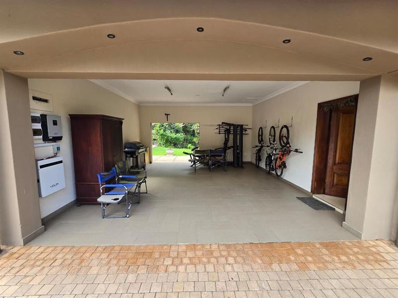 A spacious covered patio area featuring tiled flooring, recessed lighting, and an integrated inverter system, providing a versatile outdoor living space.