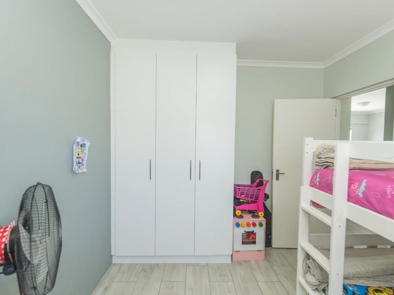 A bedroom featuring built-in cupboards, light-toned laminate flooring, and neutral wall finishes.