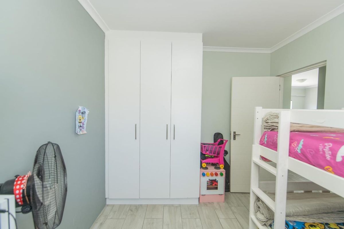 A bedroom featuring built-in cupboards, light-toned laminate flooring, and neutral wall finishes.