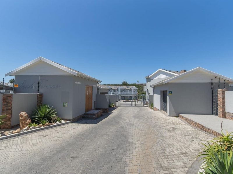 Front entrance view of the apartment complex featuring a paved driveway, secure gated access, and perimeter electric fencing.