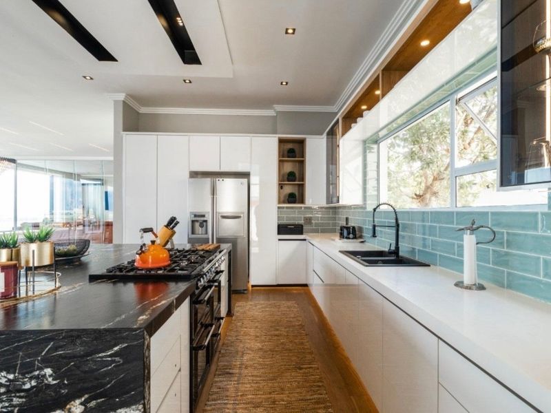 Modern kitchen featuring a large stone-topped island, gas cooktop, integrated cabinetry, and a stylish subway tile backsplash with ample natural light.