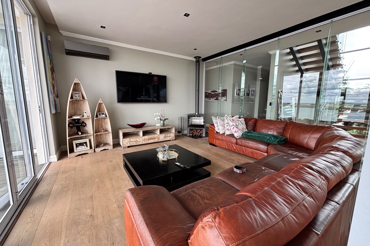 Spacious living room featuring wood flooring, a modern freestanding fireplace, recessed lighting, and large sliding glass doors leading to an outdoor area.
