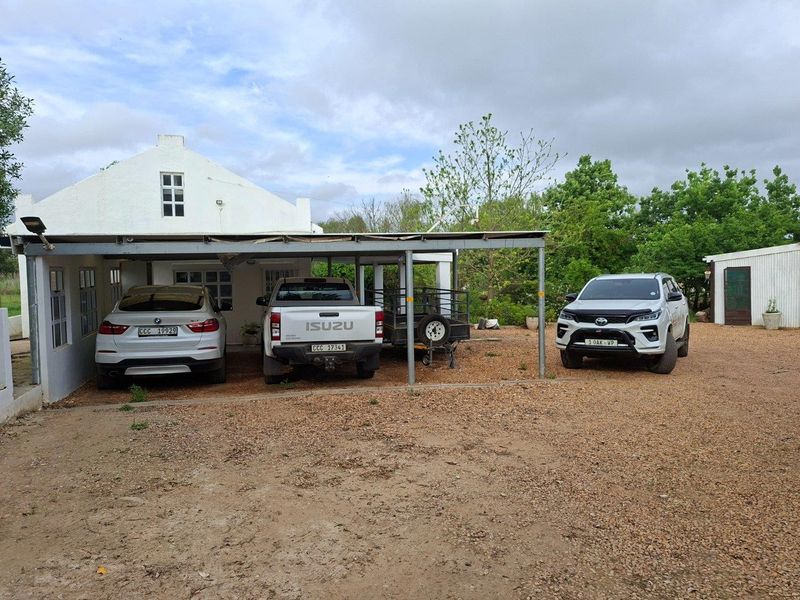 Front exterior view of the farm property featuring a covered carport area and a gravel driveway.