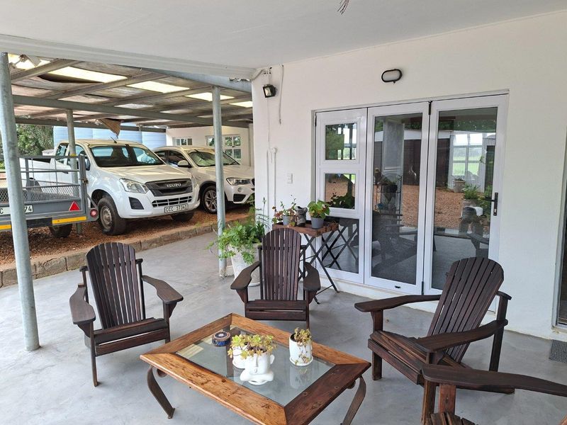 A covered patio area featuring concrete flooring and glass sliding doors, providing a functional outdoor space adjacent to a covered parking area.