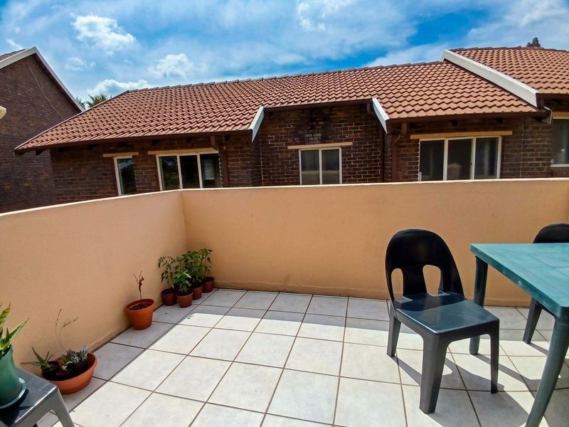 A private outdoor patio area featuring tiled flooring and a masonry boundary wall, overlooking the rear elevation of the townhouse.