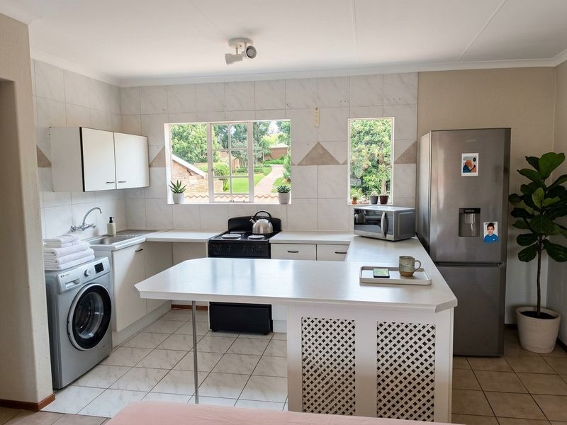 Functional kitchen featuring white cabinetry, tiled backsplash, breakfast bar, and dedicated space for a washing machine, offering a practical layout for daily use.