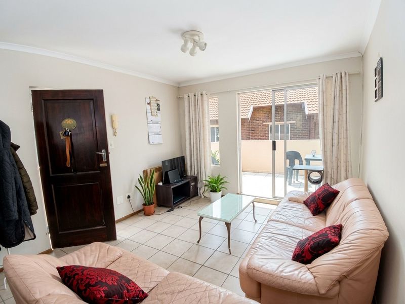 A living room featuring tiled flooring and a sliding glass door providing access to an outdoor patio area.