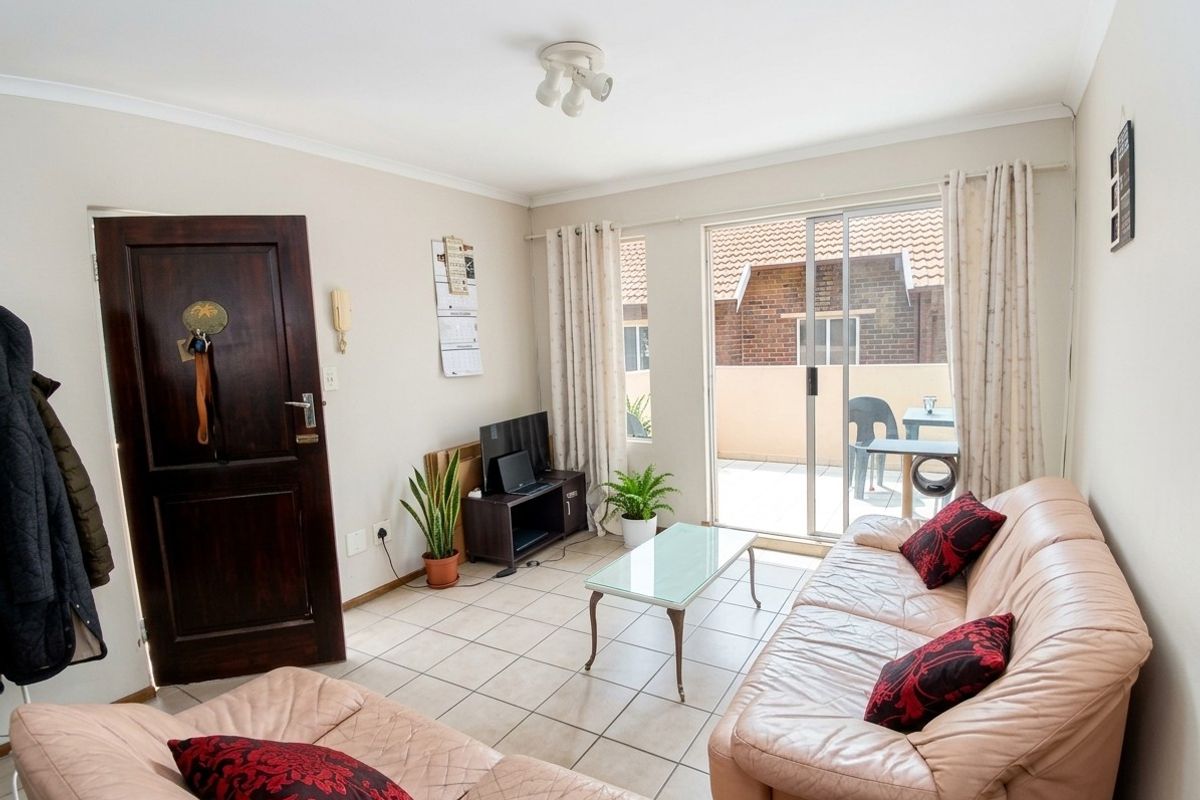 A living room featuring tiled flooring and a sliding glass door providing access to an outdoor patio area.