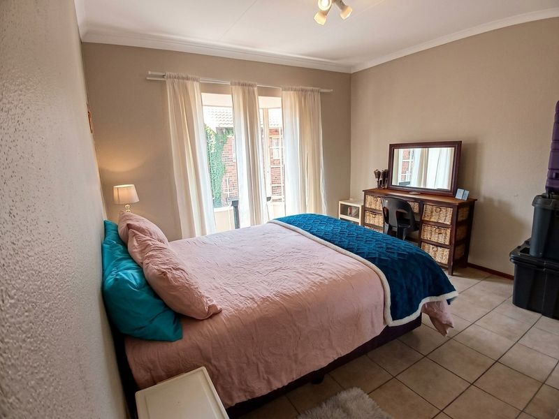 A well-lit bedroom featuring tiled flooring, coved ceilings, and a sliding glass door providing access to the exterior.