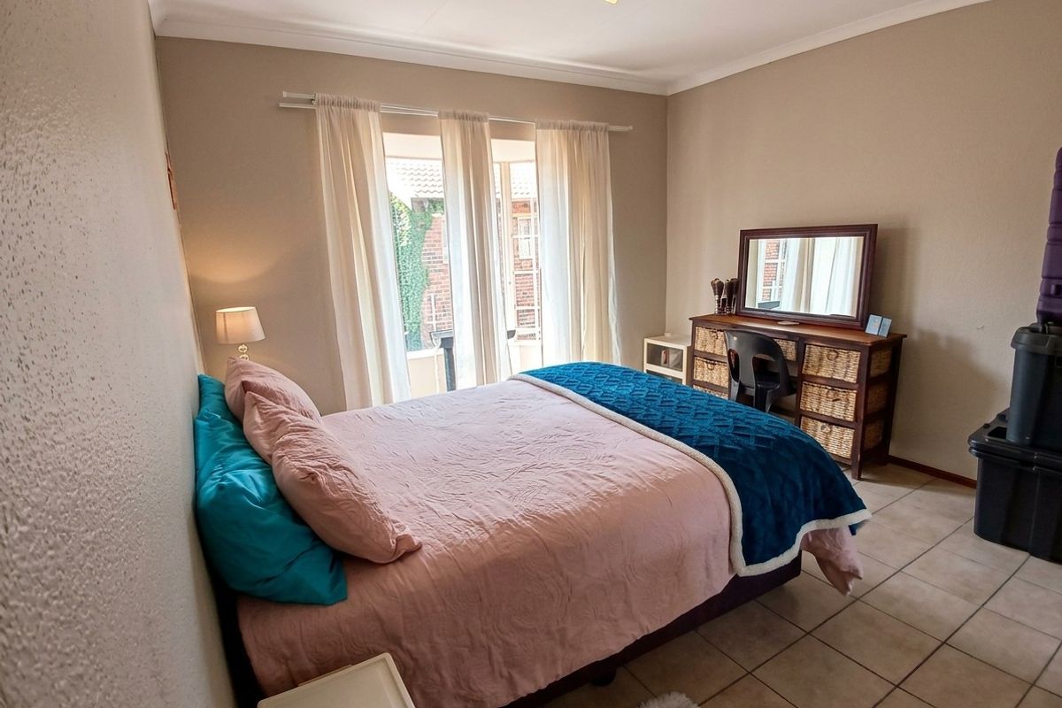 A well-lit bedroom featuring tiled flooring, coved ceilings, and a sliding glass door providing access to the exterior.