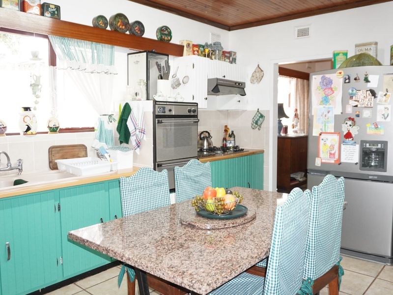A functional kitchen featuring built-in cabinetry, a tiled backsplash, integrated oven and hob, and a timber ceiling, offering a classic, lived-in aesthetic.