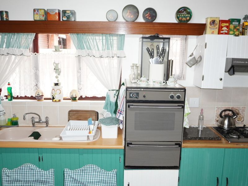 A functional kitchen featuring fitted cabinetry, wooden countertops, a built-in oven, gas hob, extractor fan, and a double sink with a tiled backsplash.