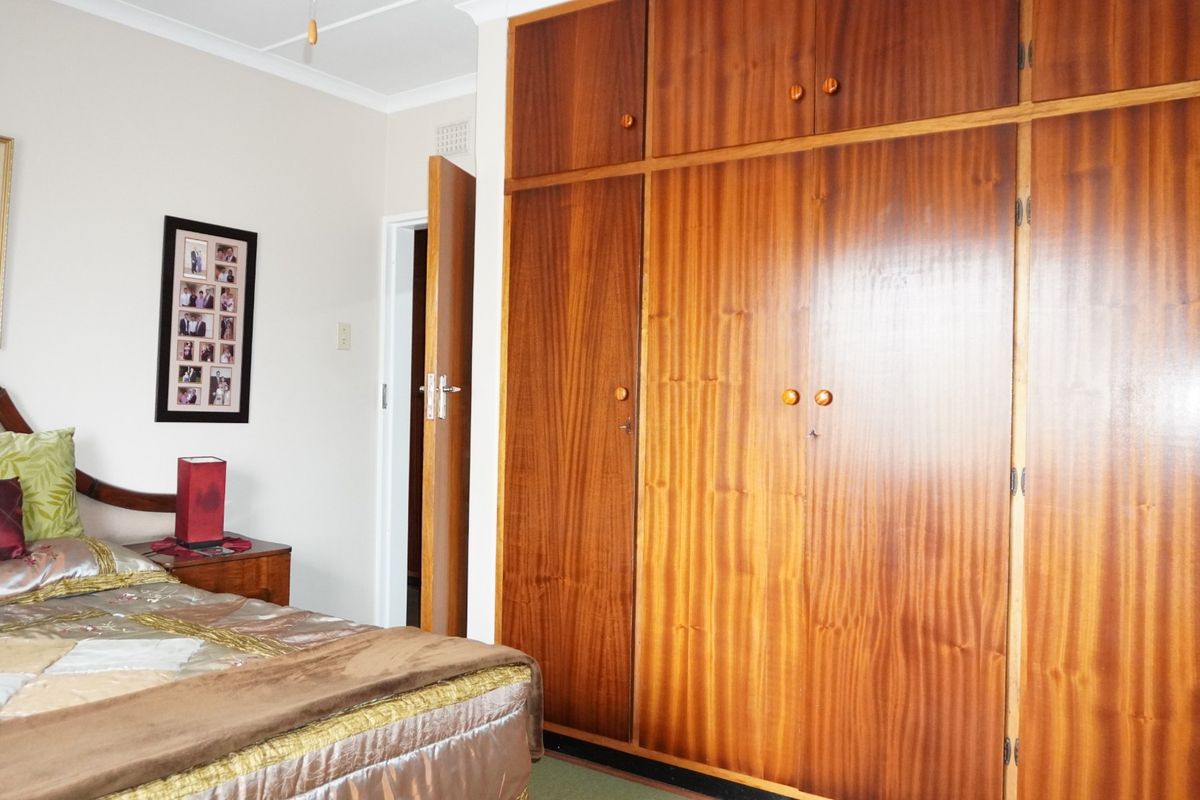 A bedroom featuring floor-to-ceiling built-in wooden cupboards and neutral wall finishes.