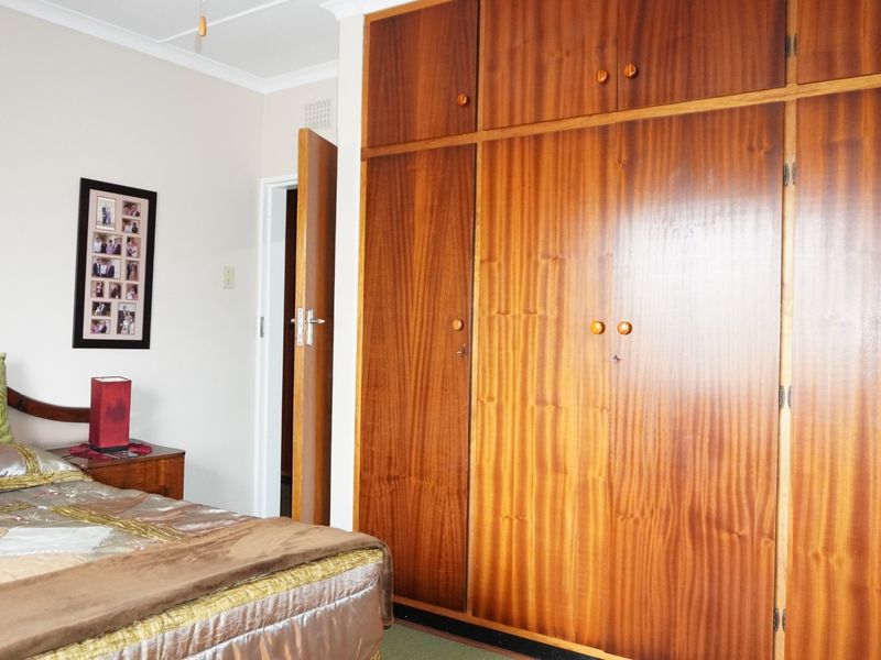 A bedroom featuring floor-to-ceiling built-in wooden cupboards and neutral wall finishes.