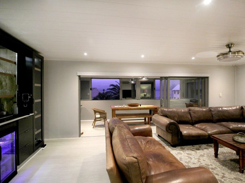Spacious living area featuring recessed lighting, a ceiling fan, and a built-in bar with integrated wine cooler, opening onto an outdoor patio.