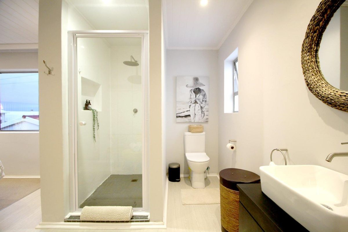 Modern bathroom featuring a glass-enclosed shower with a rain shower head, a sleek vessel sink vanity, and a contemporary toilet.