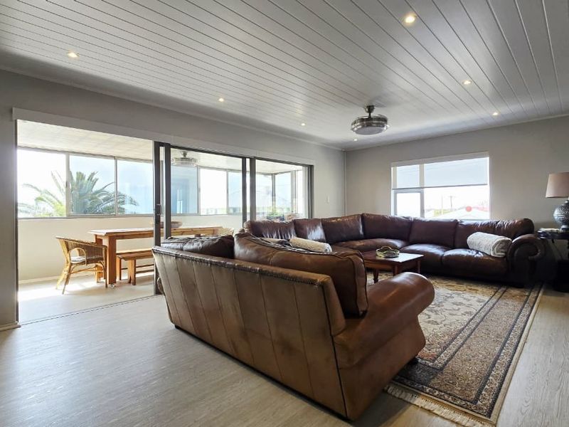 Spacious living room featuring a tongue and groove ceiling with recessed lighting, ceiling fan, and large sliding glass doors opening to an outdoor patio area.