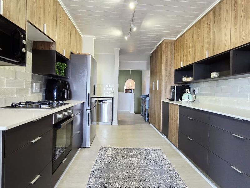 Modern galley-style kitchen featuring sleek two-tone cabinetry, quartz countertops, subway tile backsplash, and integrated appliances with a clean, contemporary finish.