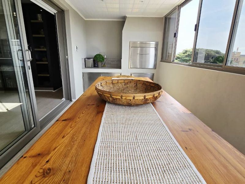 Covered balcony featuring a built-in braai, tiled flooring, and large sliding glass doors providing seamless indoor-outdoor flow.