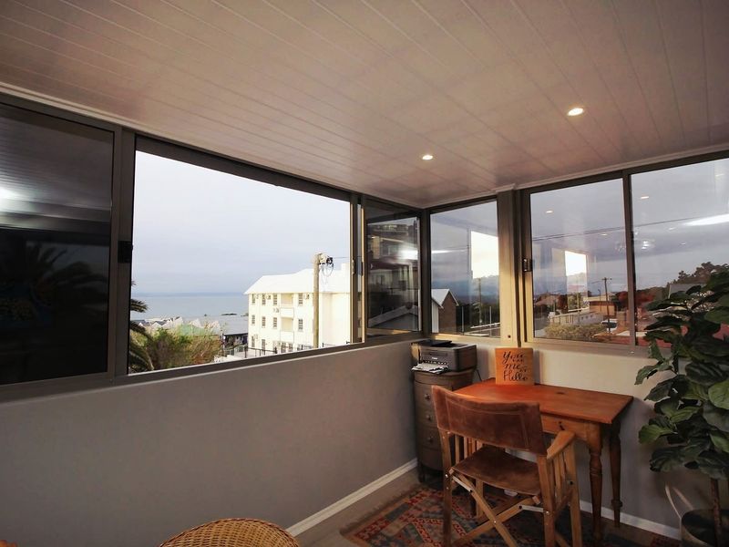 Enclosed balcony featuring large aluminium sliding windows, recessed downlighting, and a clean tongue and groove ceiling, offering elevated neighbourhood and coastal views.