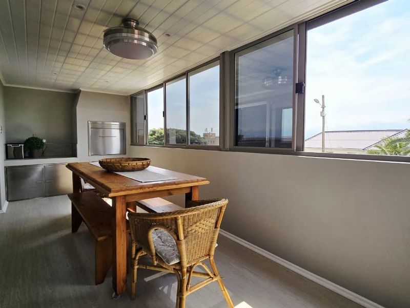 Enclosed patio featuring a built-in braai, stainless steel cabinetry, and large sliding windows providing ample natural light and outdoor views.
