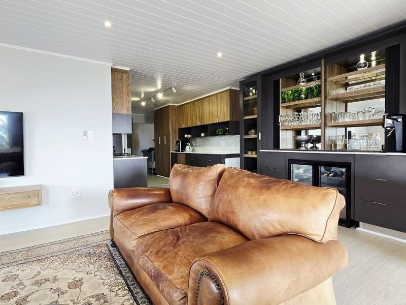 Modern open-plan living area featuring a sophisticated built-in bar with integrated refrigeration, sleek cabinetry, and a contemporary tongue and groove ceiling finish.