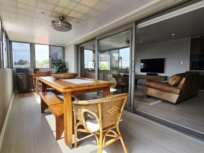 A bright, enclosed patio featuring laminate flooring, recessed lighting, and large sliding glass doors that provide seamless access to the main living area.