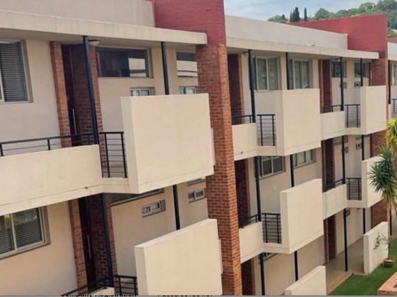 Exterior view of a multi-story apartment building featuring private balconies, brick accents, and metal railings.